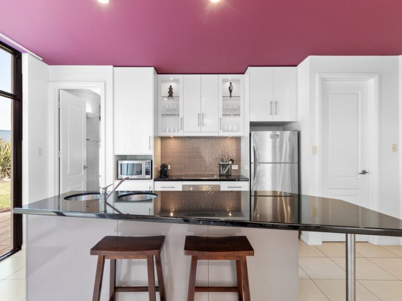 Coonawarra Experiences – Stylish kitchen with island bench, stools, and red ceiling.