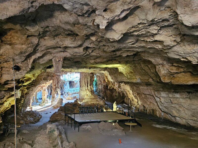 A wide view of the interior of Naracoorte Caves, featuring rocky formations and a large open area with a platform in the centre.