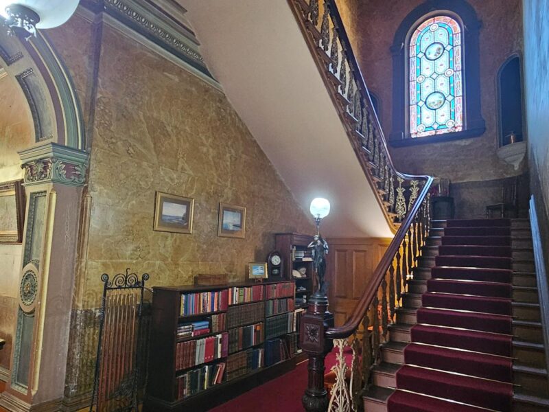 A parlour room with Victorian furniture, a piano, and intricate wallpaper at Yallum Park.