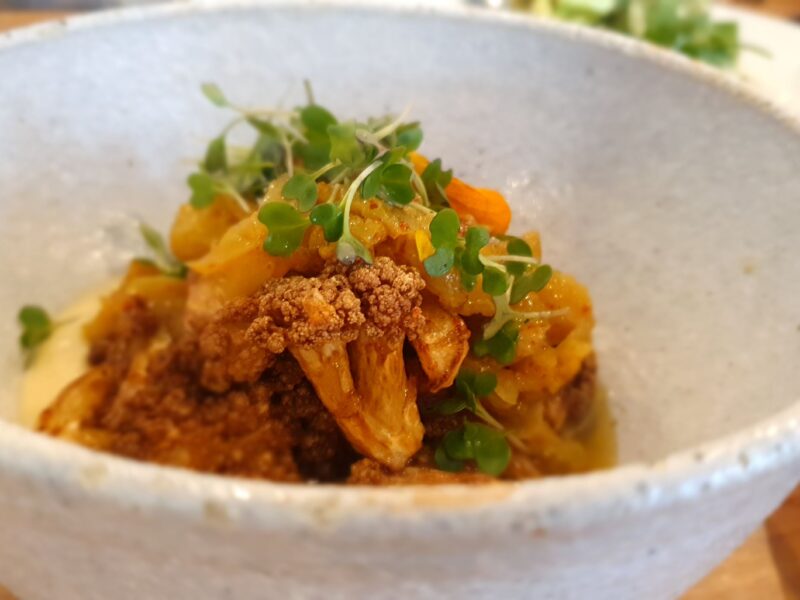 Bowl of roasted cauliflower with vibrant microgreens and a spiced garnish