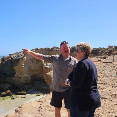 Guide pointing out coastal features to a visitor on a scenic tour, highlighting the rugged beauty of the Limestone Coast.