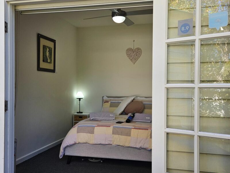 Coonawarra Experiences guest room with open French doors, queen bed, and warm natural light from the garden view.