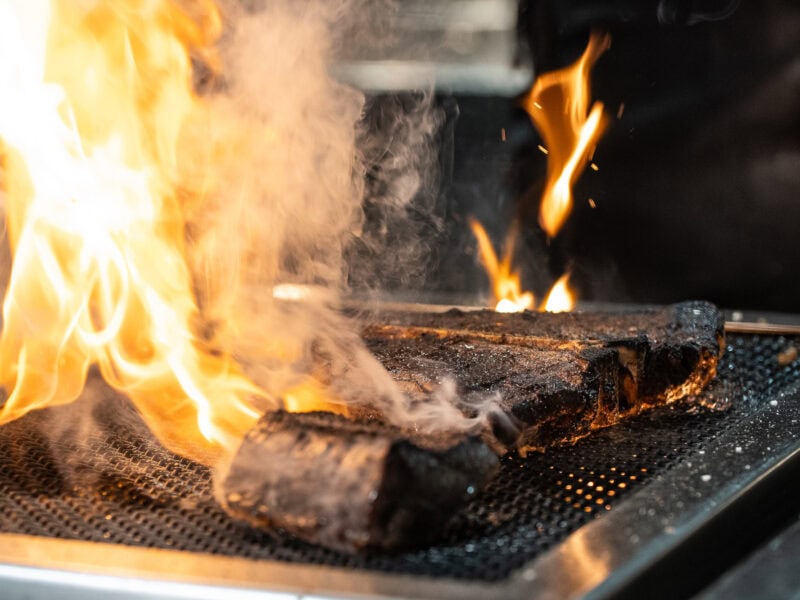 Mayura Wagyu steak cooking over an open flame grill.