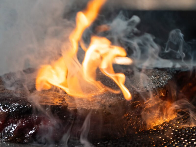 Mayura Wagyu steaks cooking over flames in the kitchen.