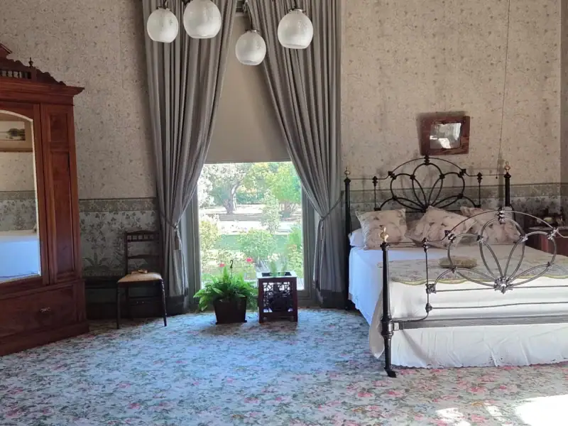 One of the grand bedrooms at Yallum Park, with original wallpaper and cast iron bed