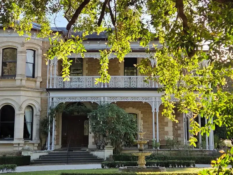 Yallum Park's sandstone Victorian mansion facade and veranda framed by overhanging tree branches, Penola South Australia